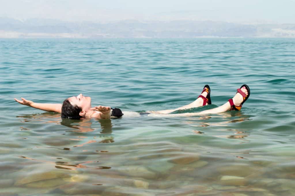 woman floating in a glassy water of dead sea with outstretched arms