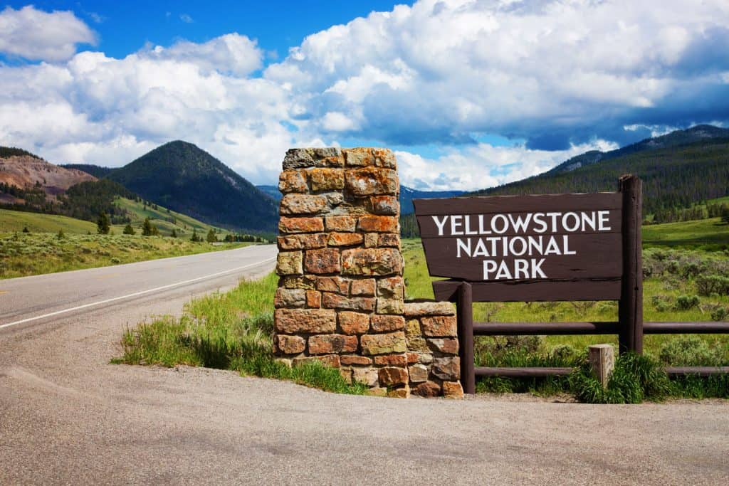 The Yellowstone National Park sign and a gorgeous scenic mountain range background