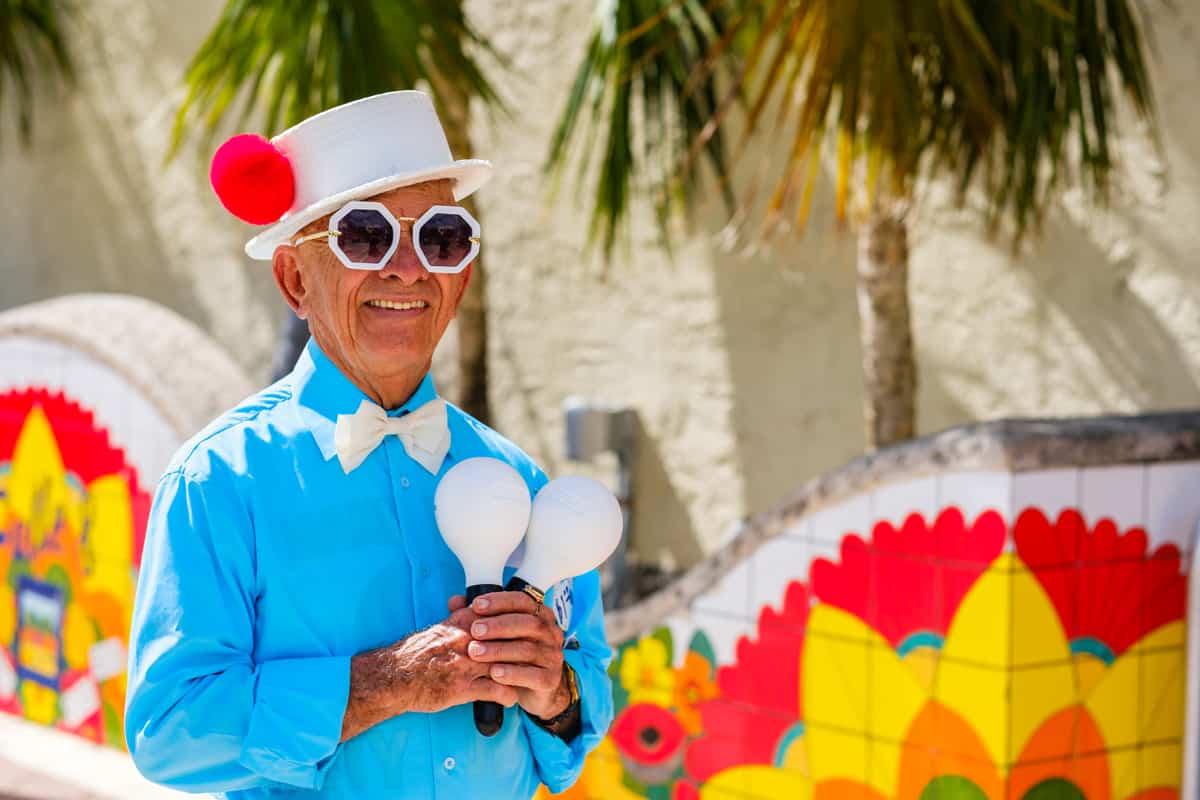 A elderly street performer holding white maracas