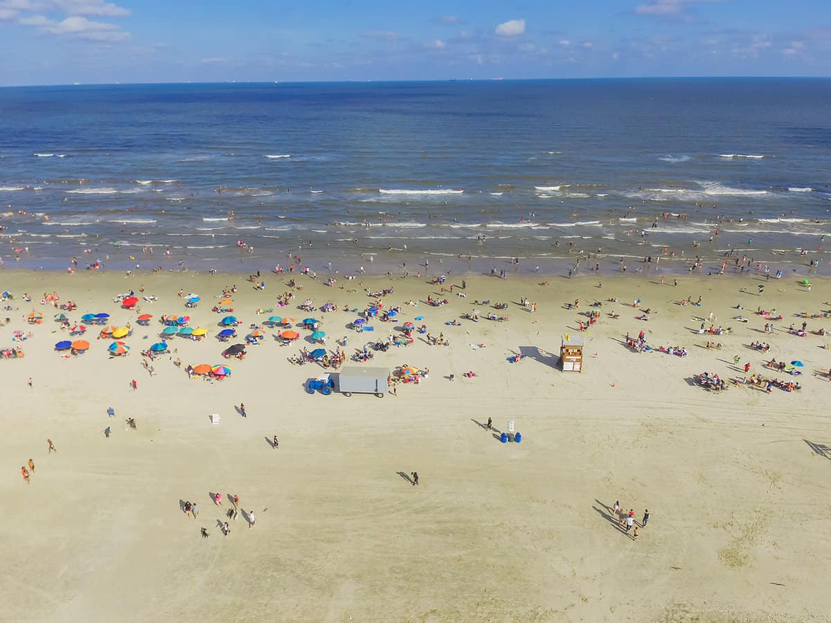 Aerial view beach shoreline on sunny summer day with people relaxing in Galveston, Texas