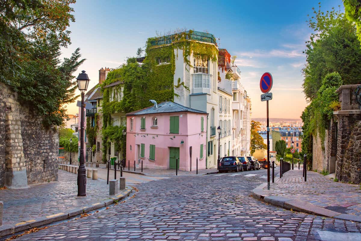 Cozy old street with pink house at the sunny sunrise, quarter Montmartre in Paris, France, Warmest Place In France In The Winter - Where To Travel?