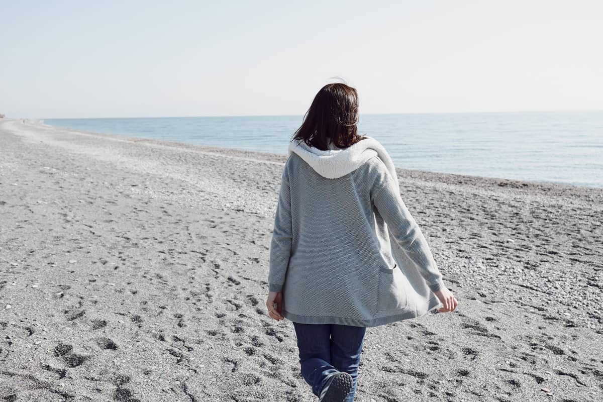 Woman wearing jacket while walking on the beach