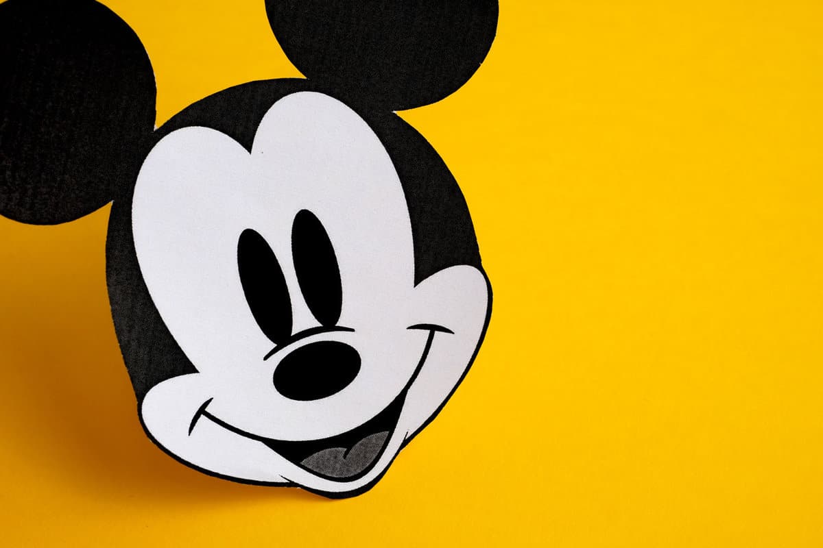 Black and white face of Mickey Mouse out of paper on a yellow background.