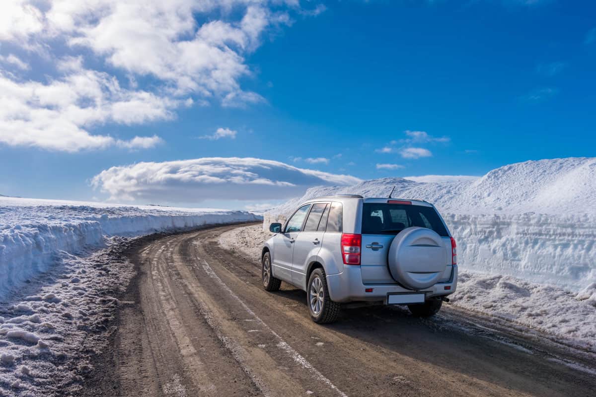 Car trekking the muddy and snow covered road of iceland