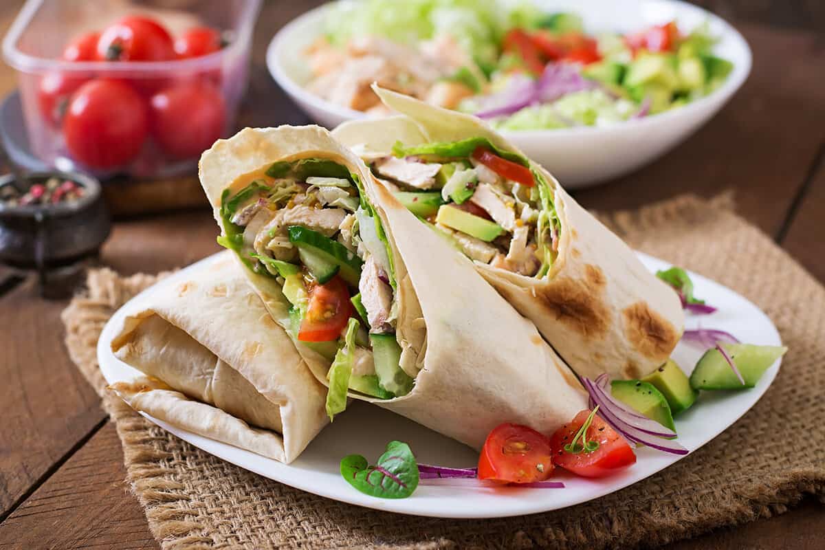 Fresh tortilla wraps with chicken and fresh vegetables on plate