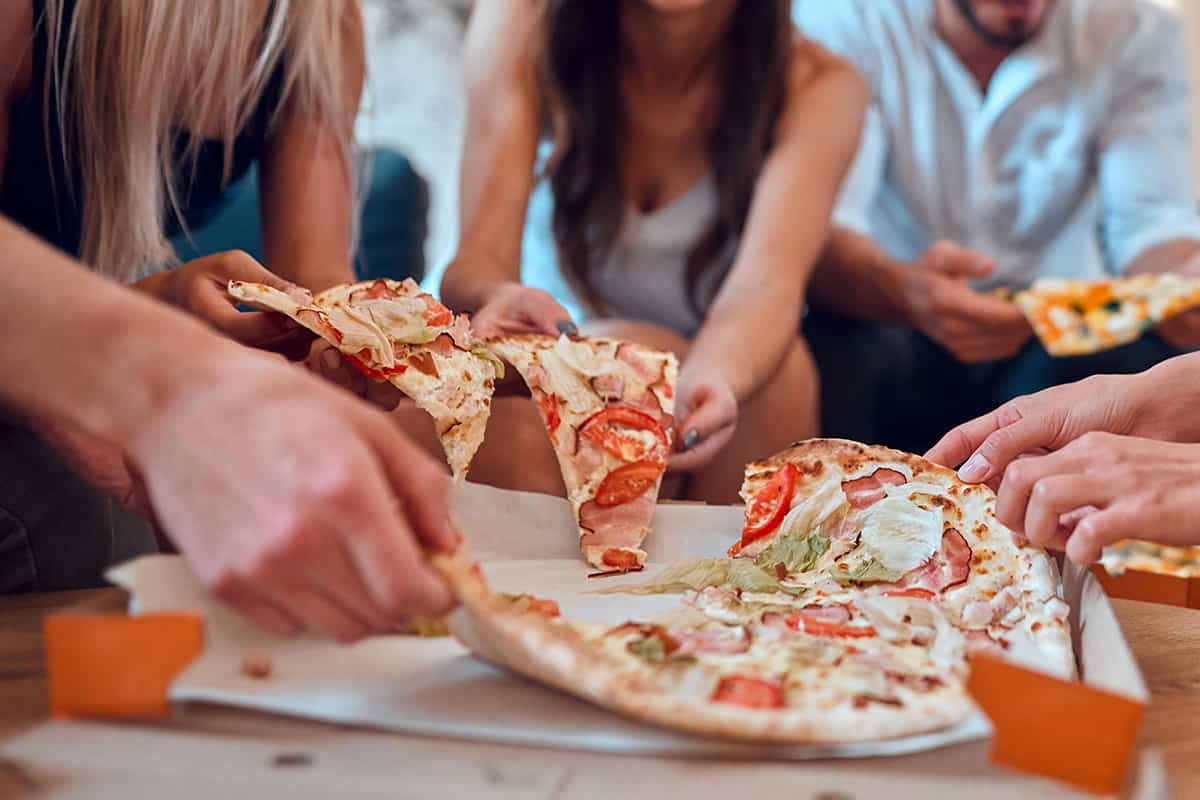 Group of young people having fun together with champagne and pizza