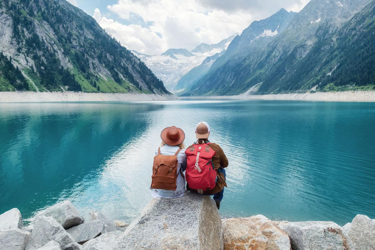 Two travelers sitting on a show while watching the scenic view of Achensee, Austria