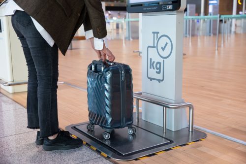 Weighing the luggage using a luggage measuring device at the airport, United Airlines: Basic Economy Vs Standard Economy Vs Economy Plus