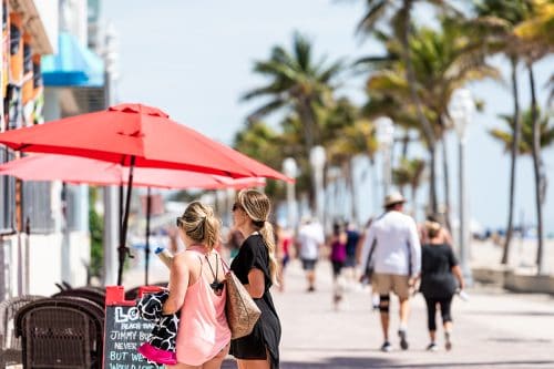 Young women on the beach boardwalk in Florida look at restaurants, Florida’s Foodie Paradise: The 3 Best Instragrammable Restaurants Statewide