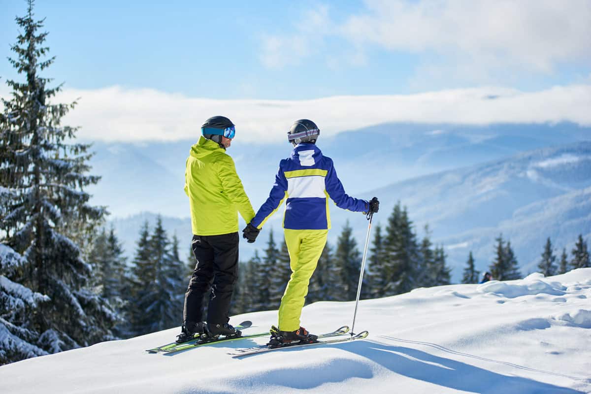 A couple holding hands while skiing at a Ski park