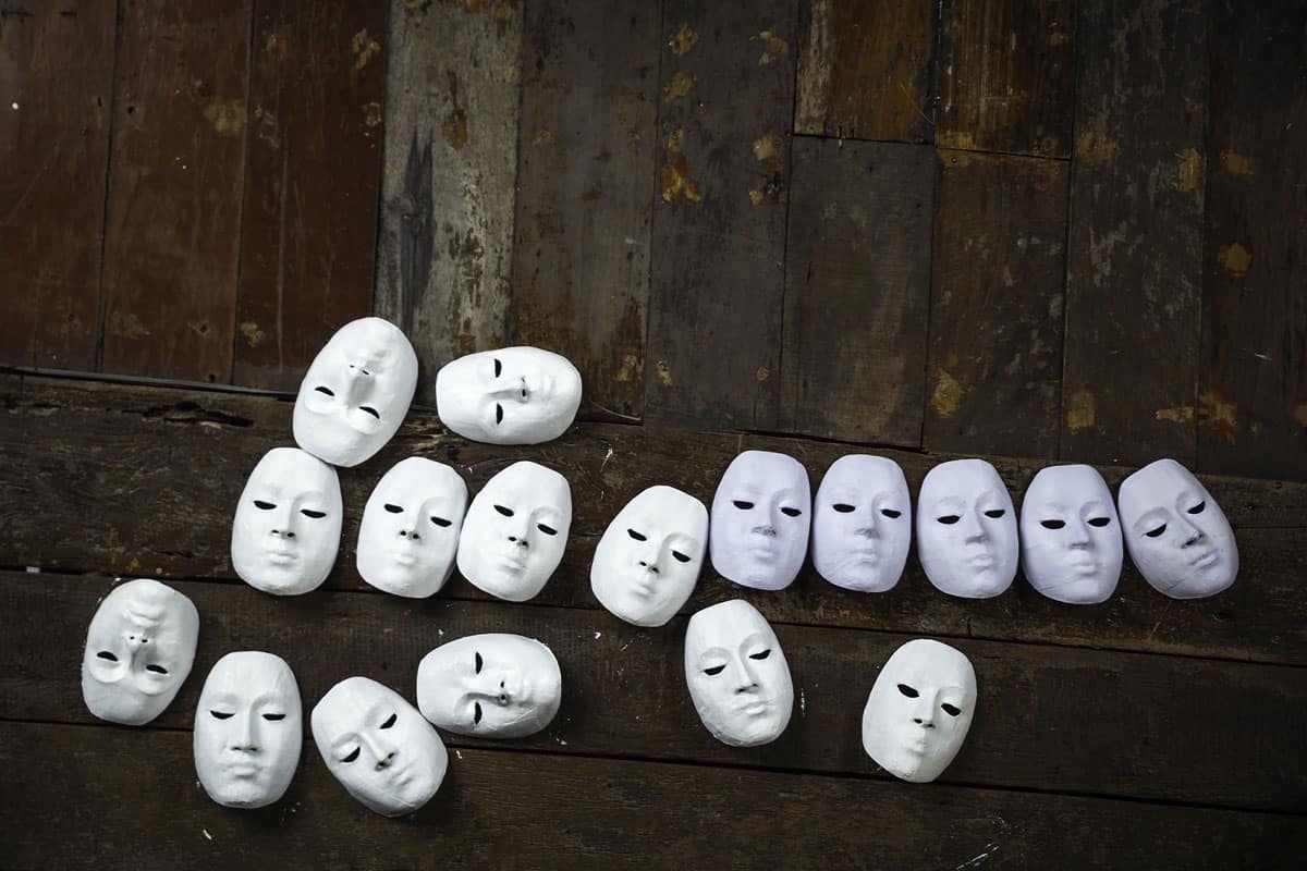 Abstract white masks on wooden background 