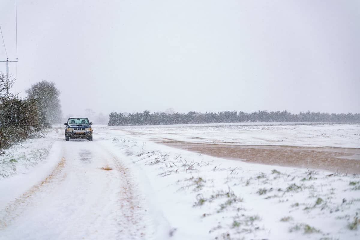 An off road truck that has broken down on a rural track in the middle of a snow storm and has been abandoned by the driver