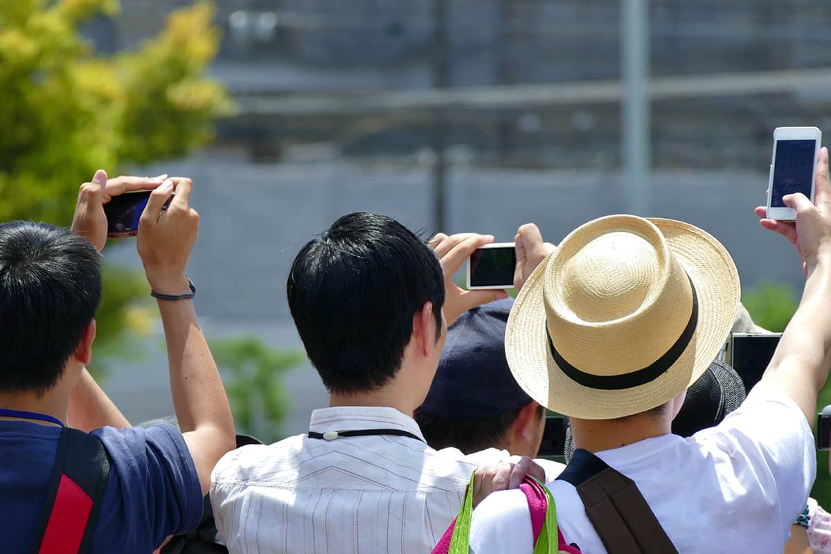 Group of people taking photo of events using mobile phone