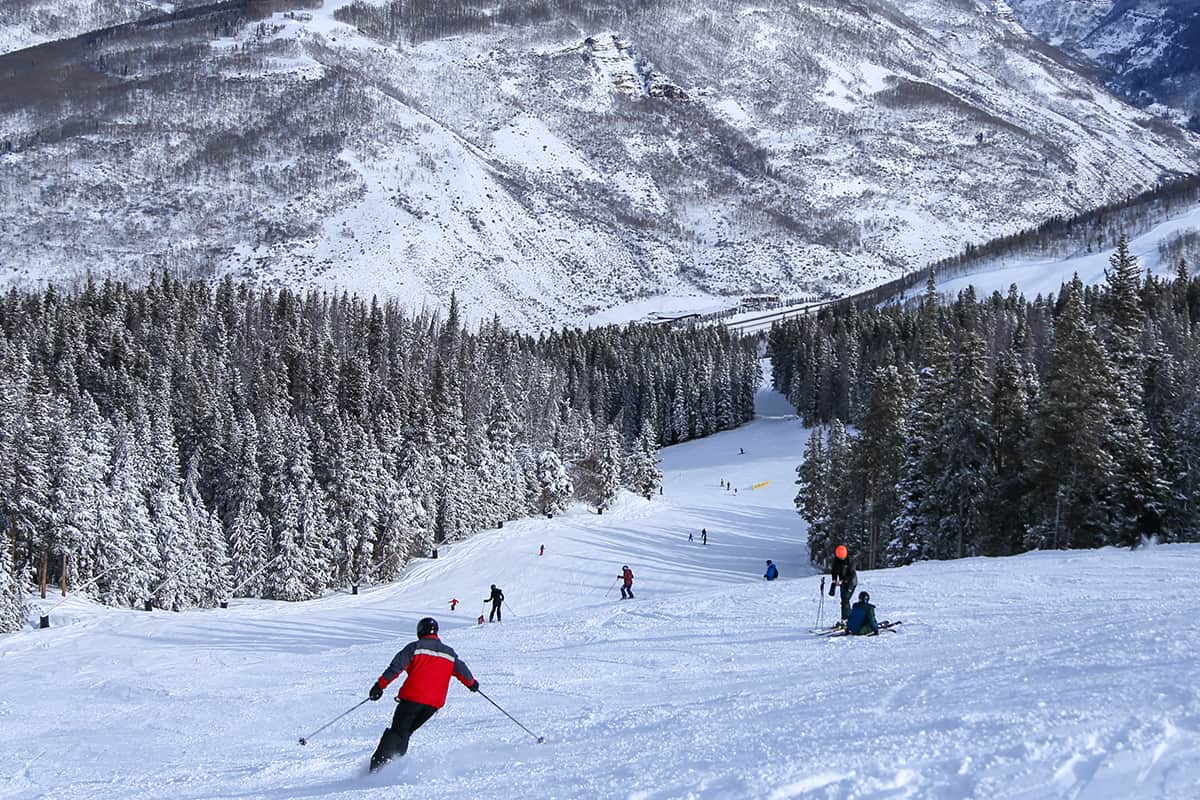 People alpine downhill skiing on trail at vail ski resort in the colorado rocky mountains in winter