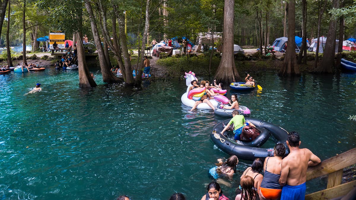 People playing and swimming in water with inflatable unicorn in Ginnie Springs, Florida