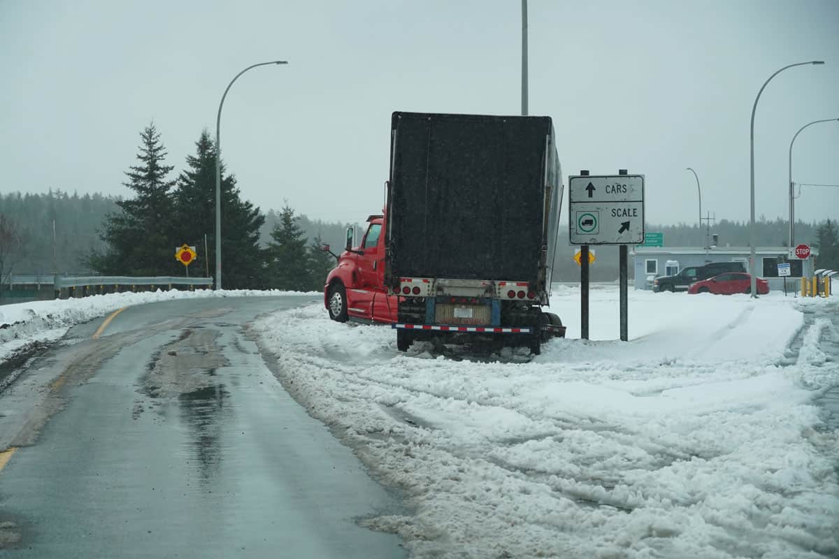 Semi truck off the road at check station during bad road conditions and accidents in first winter storm of the season