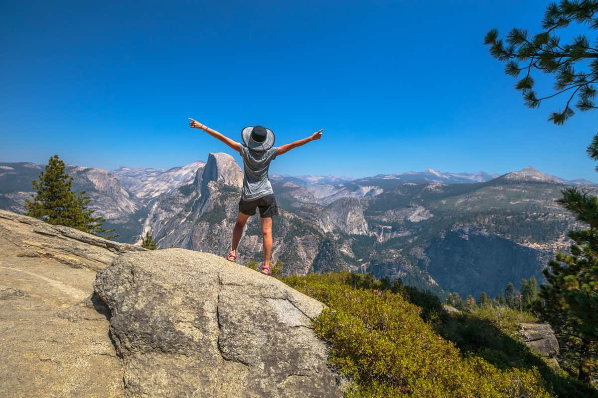 Travelling enthusiast woman happy for the Glacier Point aerial view in Yosemite National Park, California, US. Glacier Point panorama Half Dome, Liberty Cap,