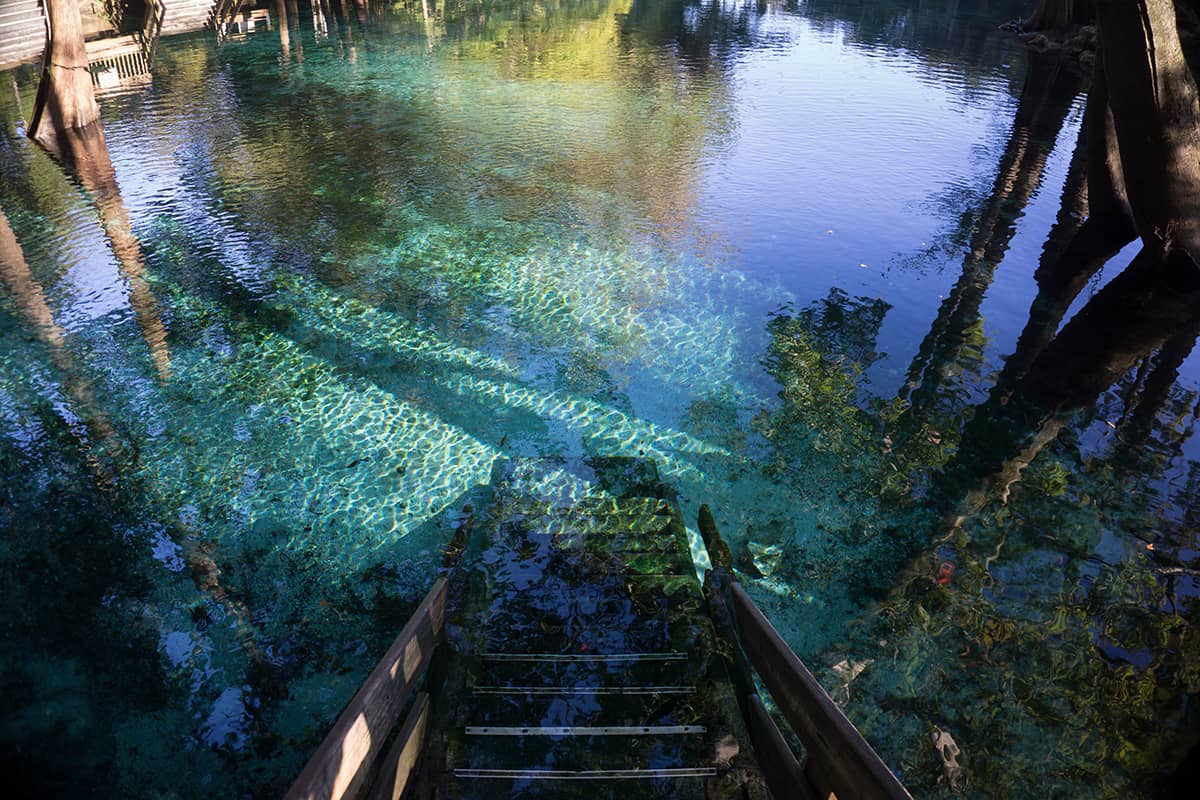 Wooden staircase steps going down to the crystal clear turquoise water of Ginnie Springs, Florida, Recharge Your Spirit and Immerse Yourself in the Natural Beauty of Florida's Clearest and Most Sought-After Clear Springs