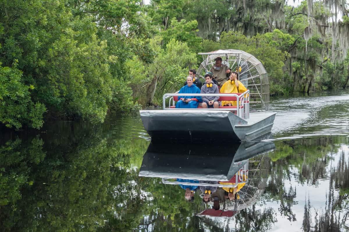 A group of people take an airboat swamp tour, a popular attraction of tourists to the area to enjoy the scenery and wildlife, including numerous alligators.