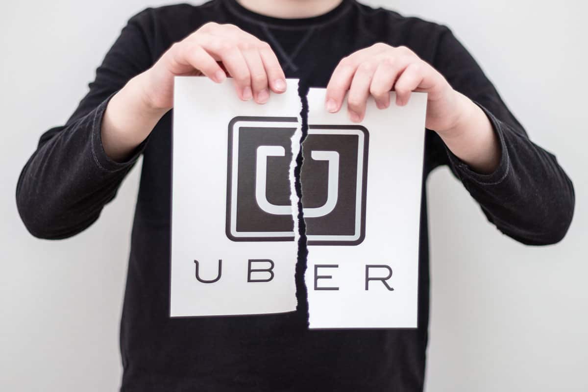 Boy breaks the logo of the world famous social service Uber, printed on paper. Concept. World problem for taxi.