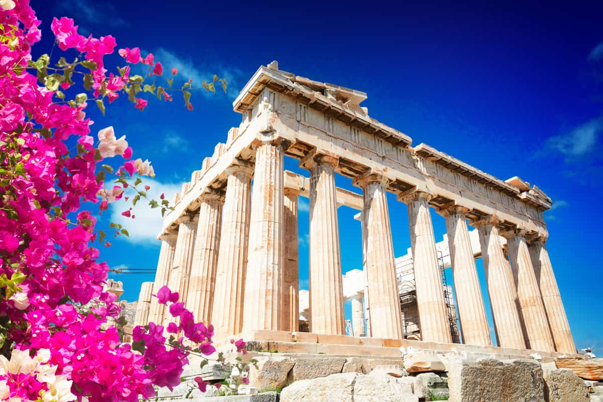 Parthenon temple over bright blue sky background, Acropolis hill, Athens Greecer with flowers