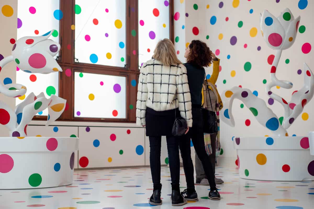 Two women watching the work of art of Yayoi Kusama, Yayoi Kusama's Polka Dot Art Takes Over Paris