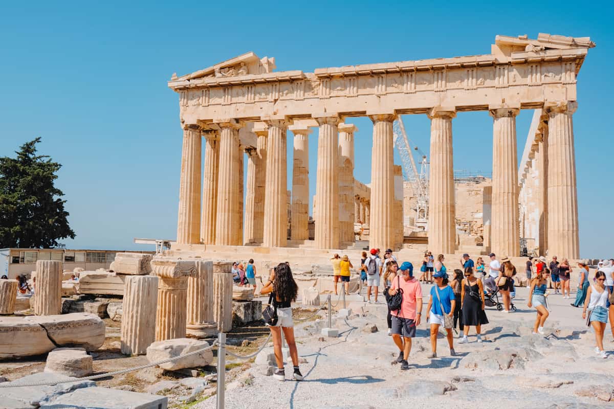 Visitors in the Acropolis of Athens, Greece, want to look closely the remains of the famous Parthenon, on a sunny summer day