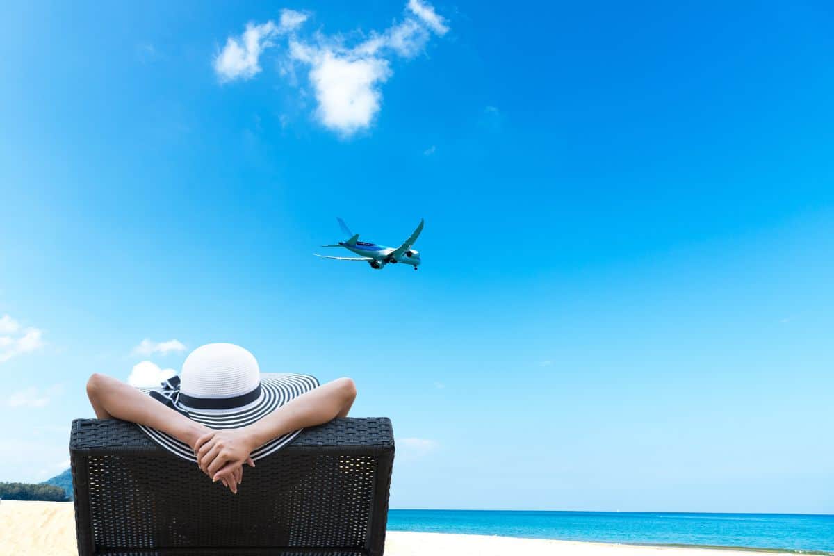 Young woman relaxing and see airplane landing on the airport near beautiful beach. Summer Concept. - Thrills and Chills: The Adrenaline Rush of Maho Beach's Low-Flying Planes