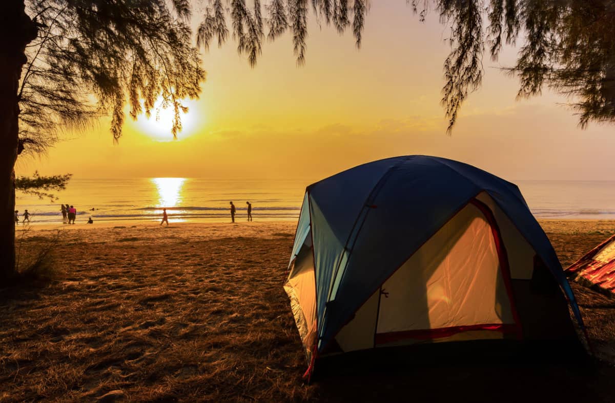 camping tent and activity on the beach in the morning with golden sky and sunrise