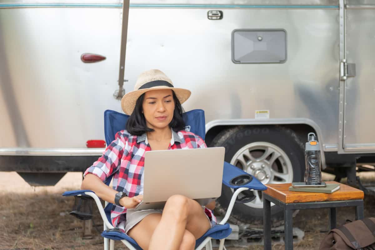 Woman looking at the laptop near the camping