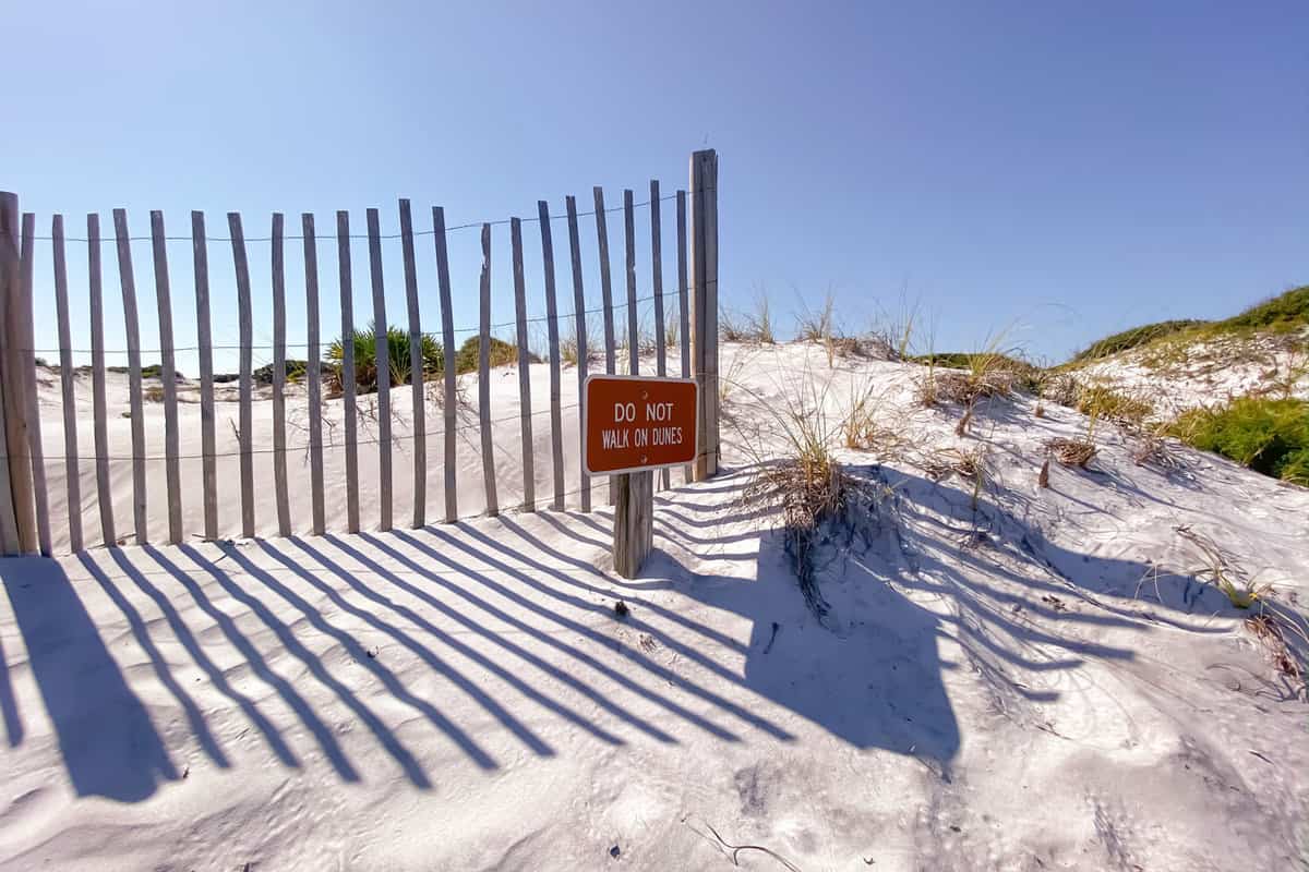 White sand dunes with sign to sat off dunes at Grayton Beach State Park in Florida