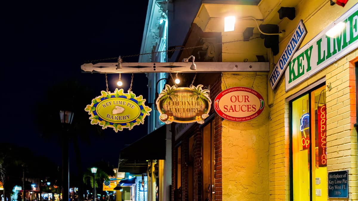Hanging vintage retro style signs for small business store shops selling key lime pie cake dessert in Florida at night on street