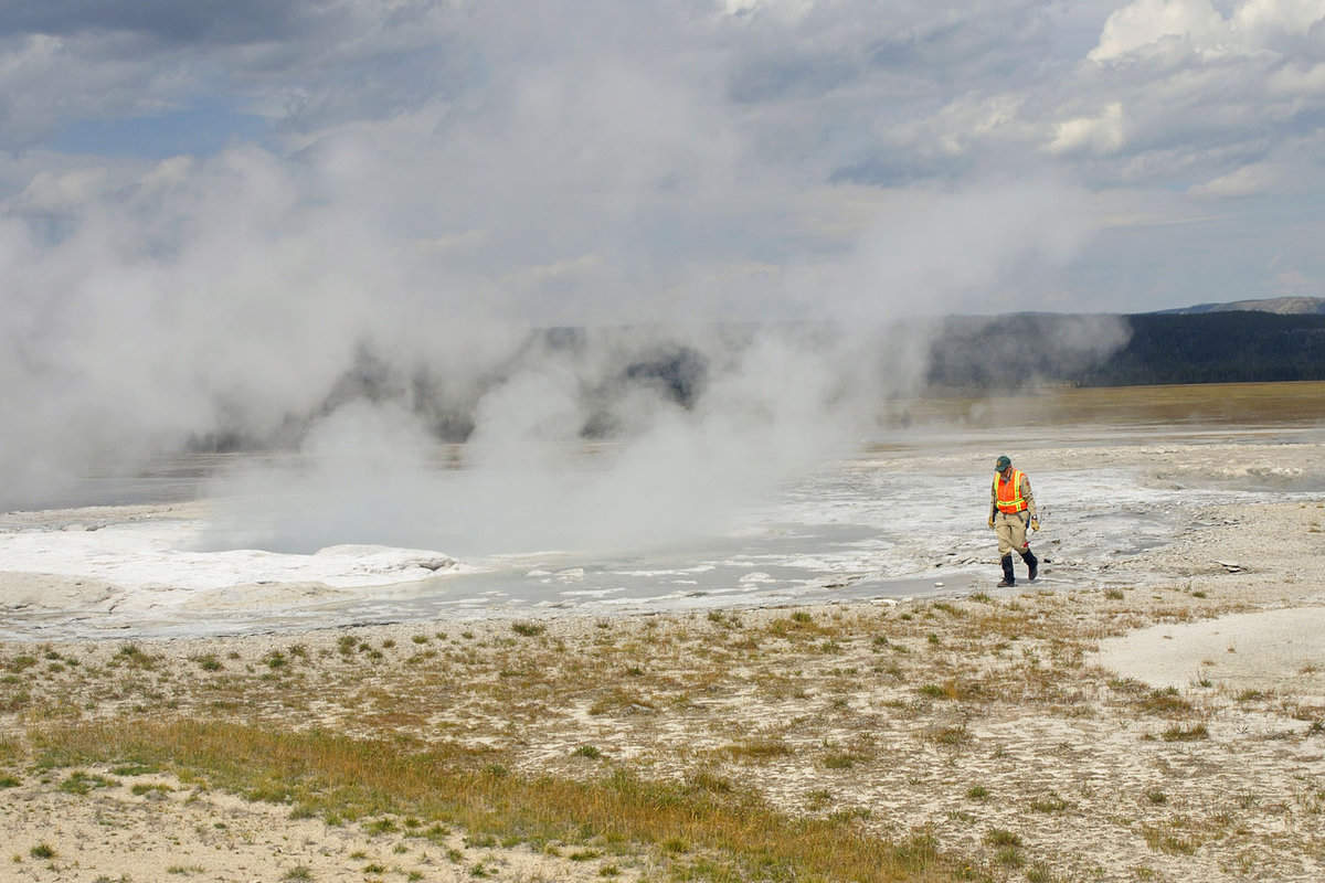 A Park Ranger walking close to a Geyser in Yellowstone National Park