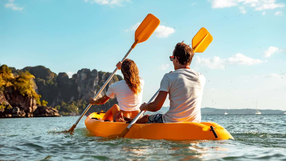 Sea kayaking or canoeing concept with young couple kayakers at tropical bay