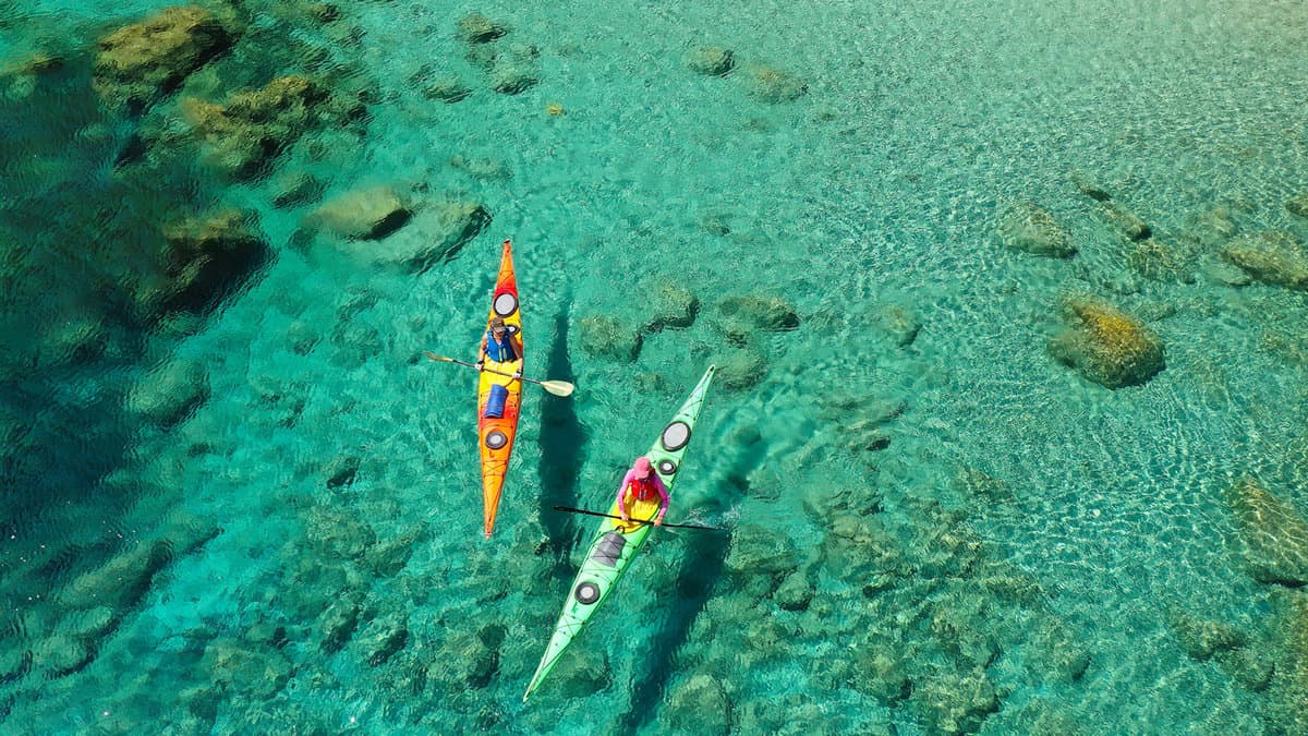 women team of sport kayak paddling in iconic beach and small cove of Tsigrado 1600x900