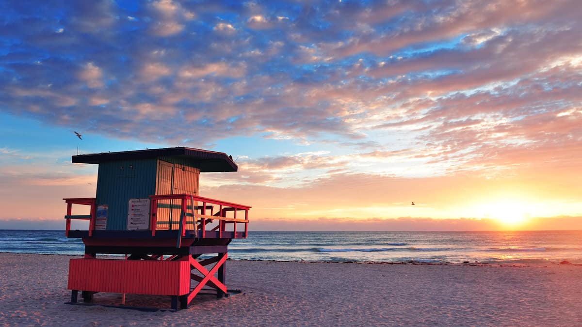 Miami South Beach sunrise with lifeguard tower and coastline with colorful cloud and blue sky