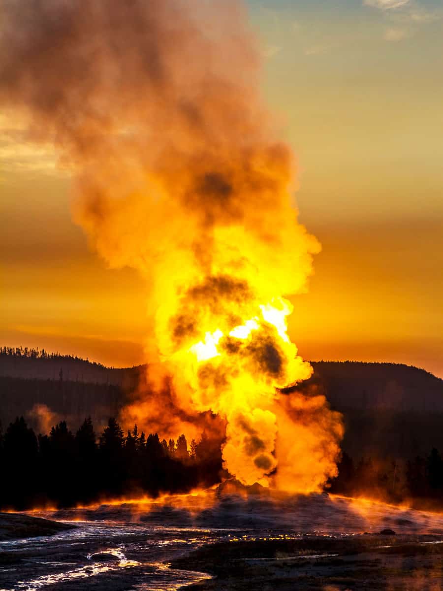 Old Faithful, Yellowstone National Park, USA, geyser steaming in the morning with sunrise behind steam in warm colours