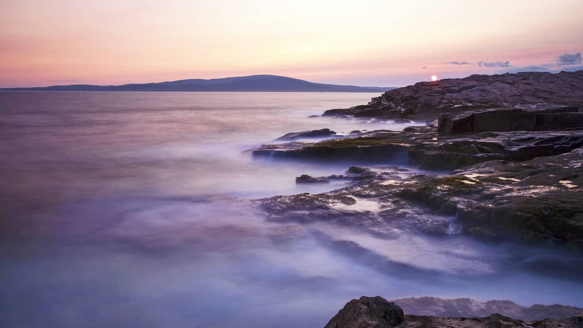 The sun sets against a rocky coast at Schoodic Point in Acadia National Park, Maine