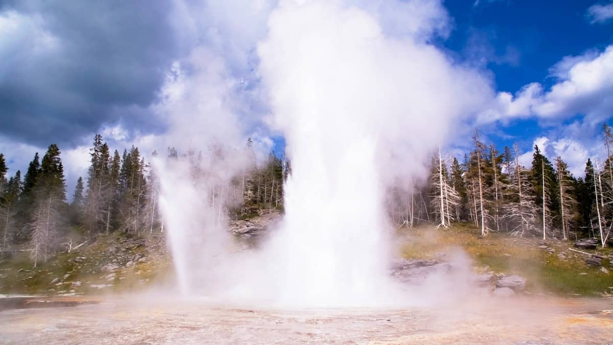 Yellowstone Grand geyser erupting on background of blue sky and clouds