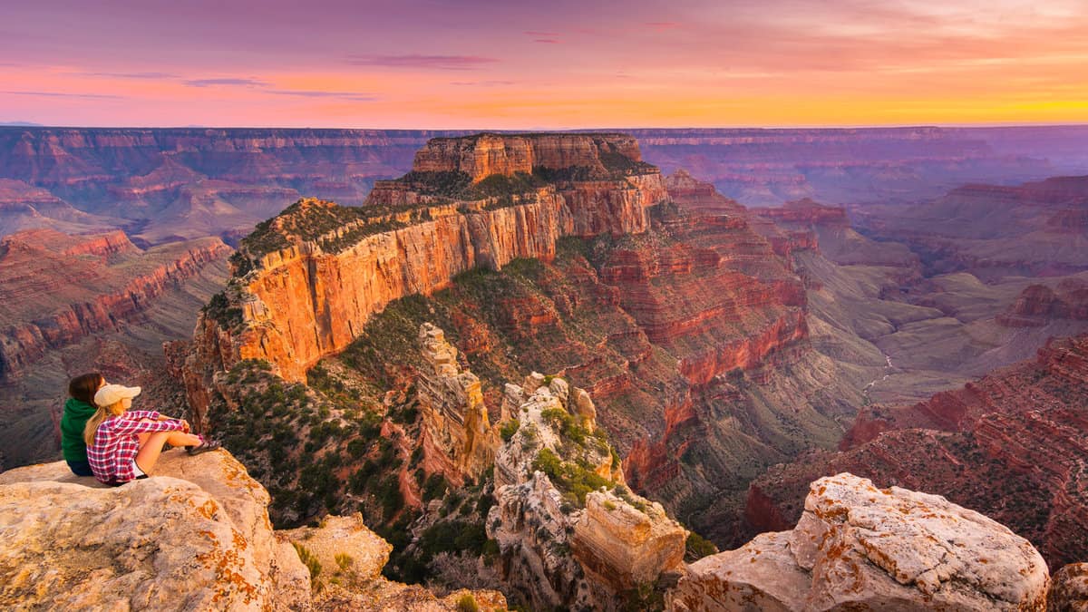 a group of people was sitting near the edge watching sunset at Grand Canyon National Park North Rim, USA