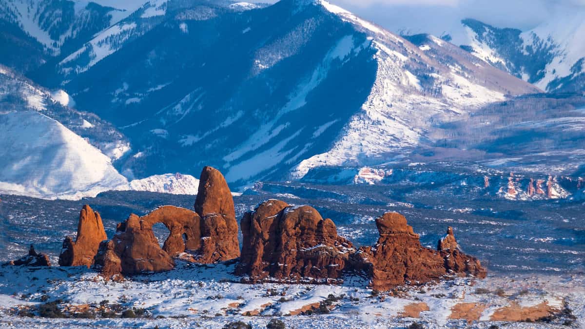 Arches rock formations near snow capped mountains in winter. Arches National Park covered with snow