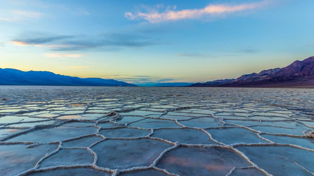 Badwater Basin at Sunset. Salt Crust and Clouds Reflection. Death Valley National Park