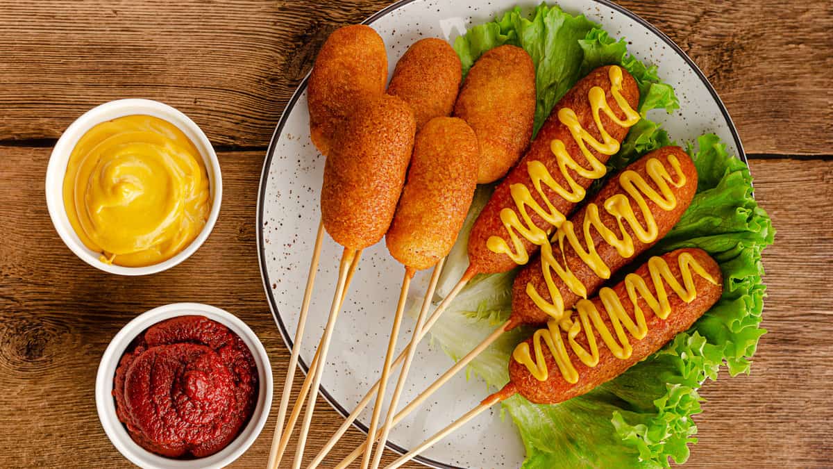 Deep fried corn dogs with mustard and ketchup on wooden background 1600x900