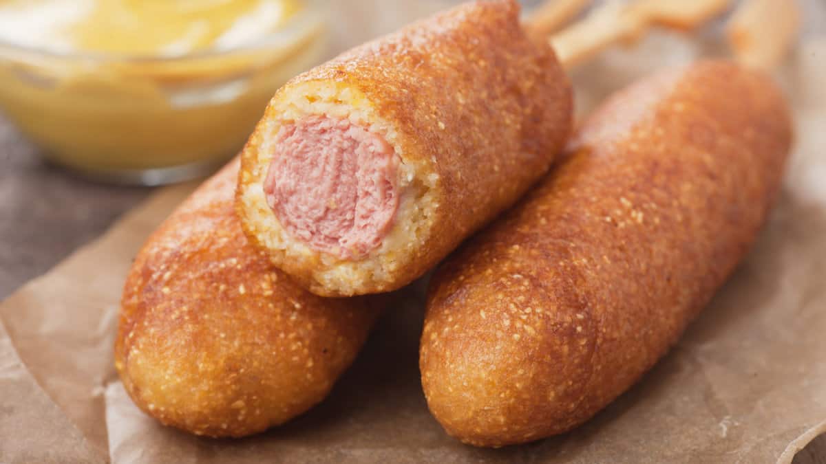 Home made corn dog fried sausage skewer with mustard
