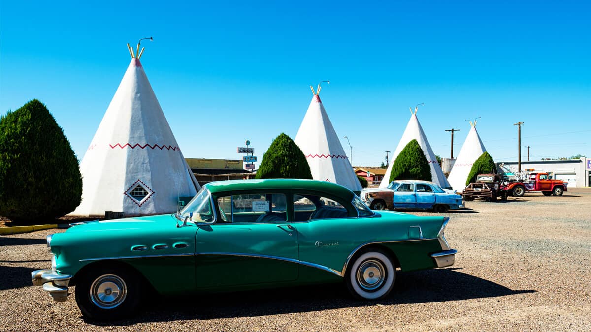 The iconic and vintage Wigwam Motel, a popular tourist destination, with tipi style motel rooms and classic cars along the historic Highway Route 66 1600x900
