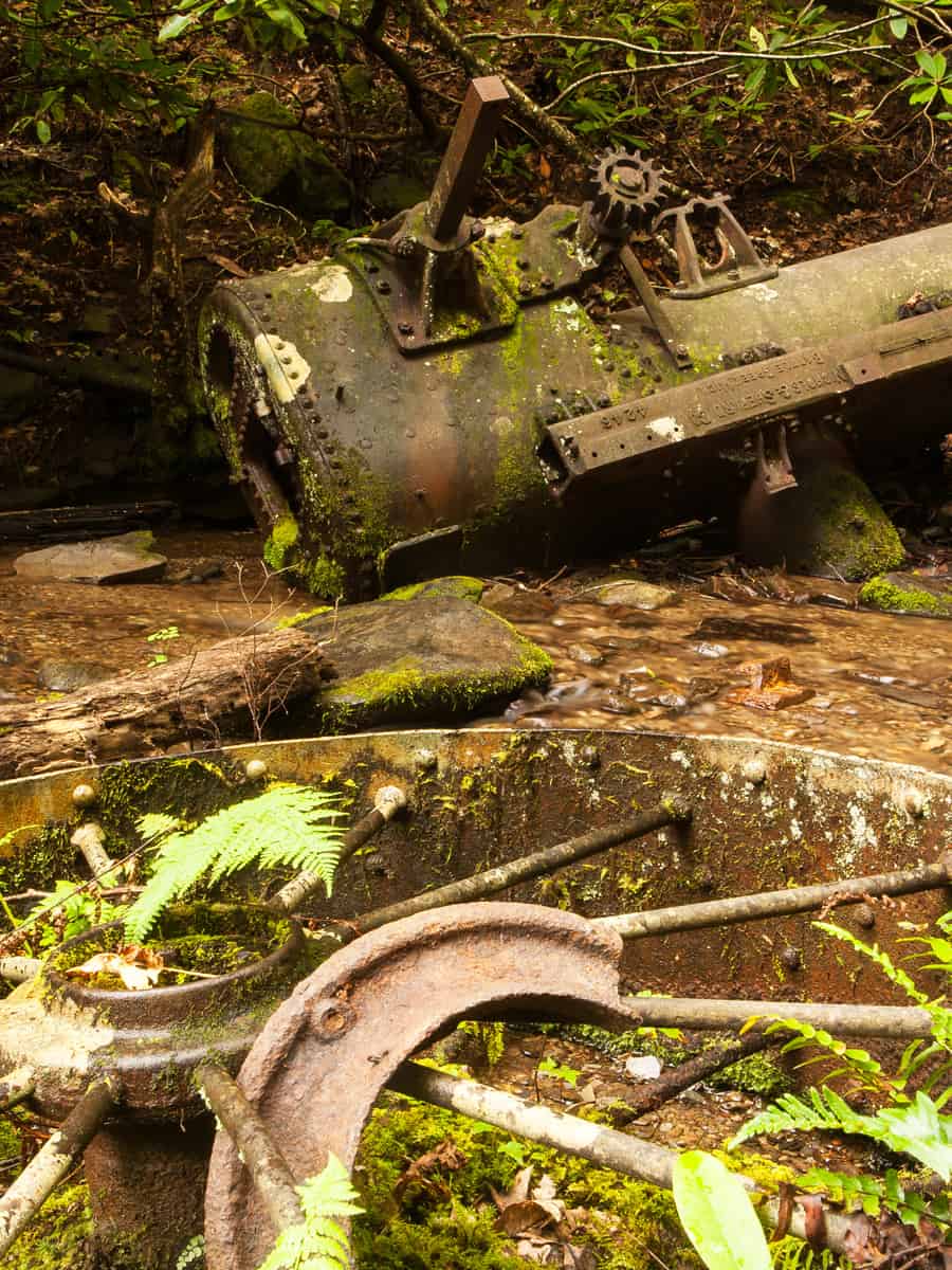 An old rusted steam engine laying in a creek, surrounded by parts. Great Smoky Mountains National Park, TN, USA.