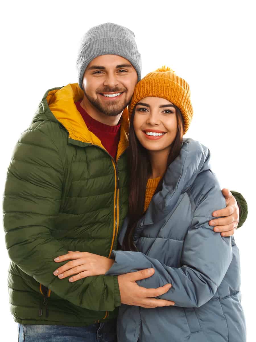 Happy young couple in warm clothes on white background. Winter vacation