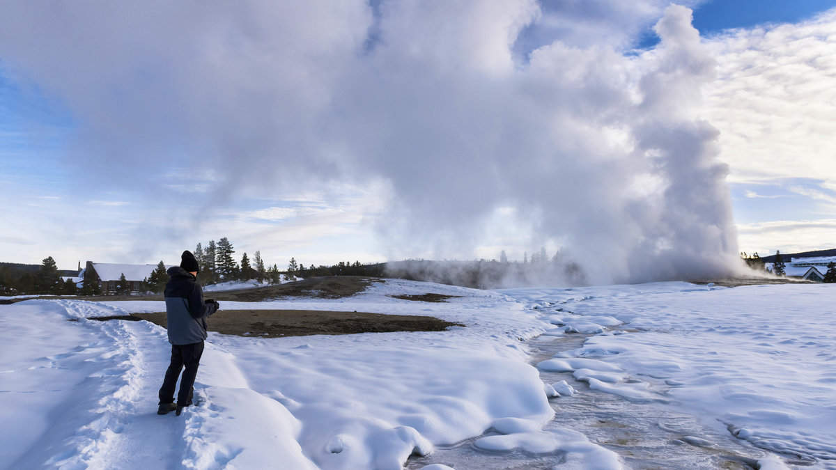 Man Taking Photo of Old Faithful at Sunset in Winter1600x900