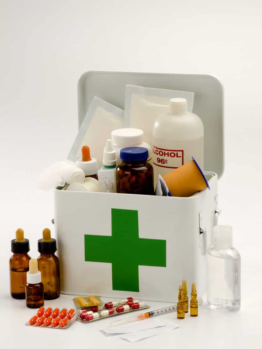 Open first aid kit filled with medical supplies in white background