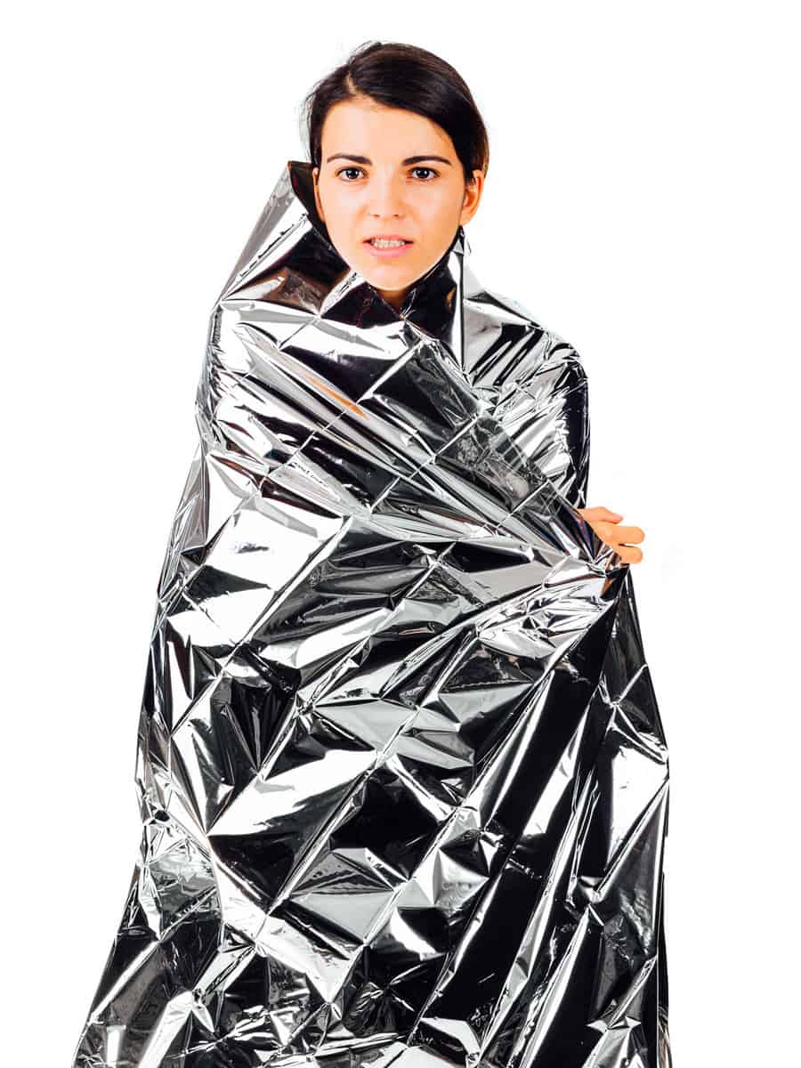 Pose of a beautiful frozen woman wearing an emergency foil over her body- isolated on white.